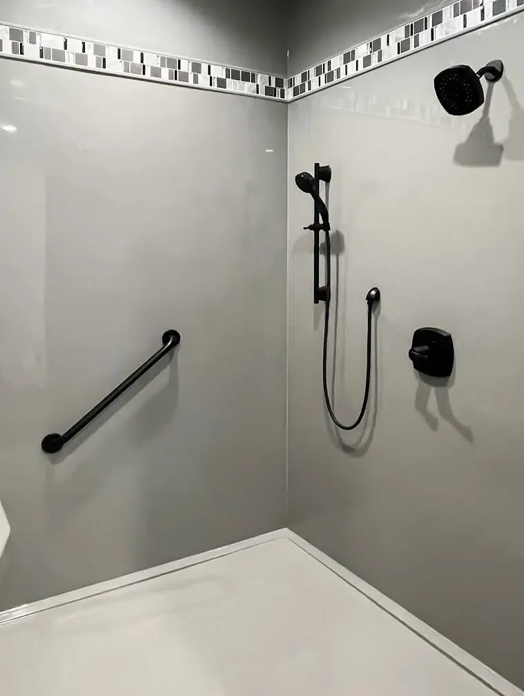 Gray panel shower with mosaic accent band, grab bar and handheld shower